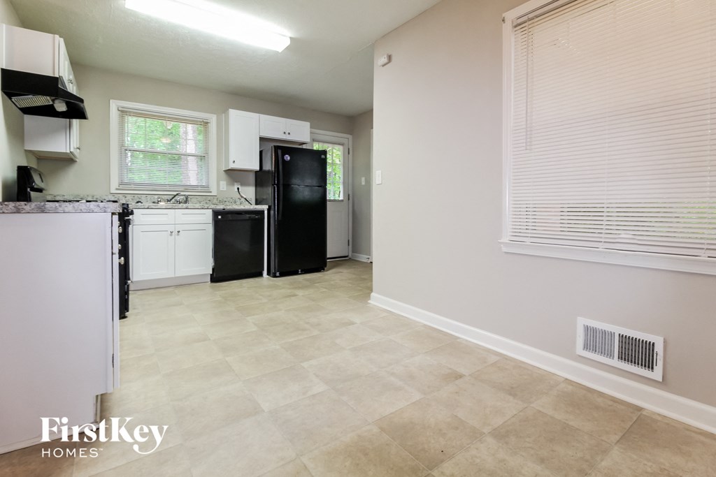 a kitchen with white cabinets and a black refrigerator