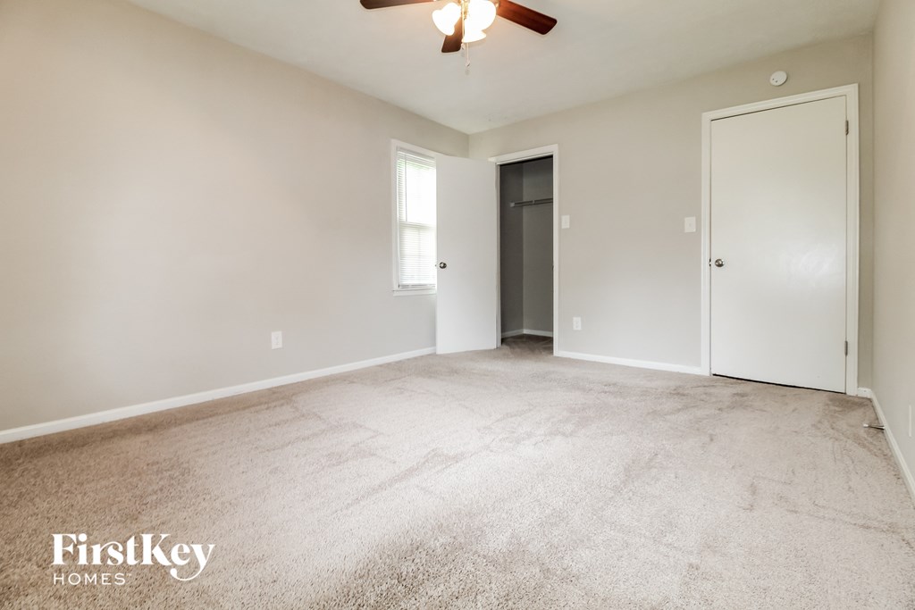 an empty living room with a ceiling fan and a door to a closet