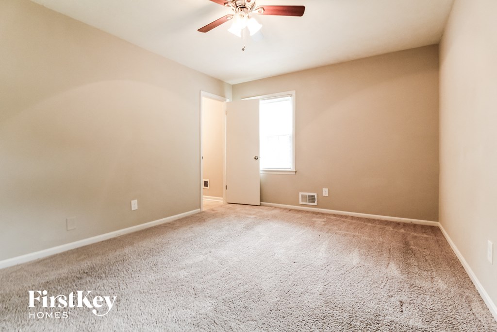 the spacious living room with carpet and ceiling fan