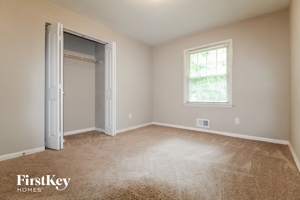 a room with carpet and a closet and a window