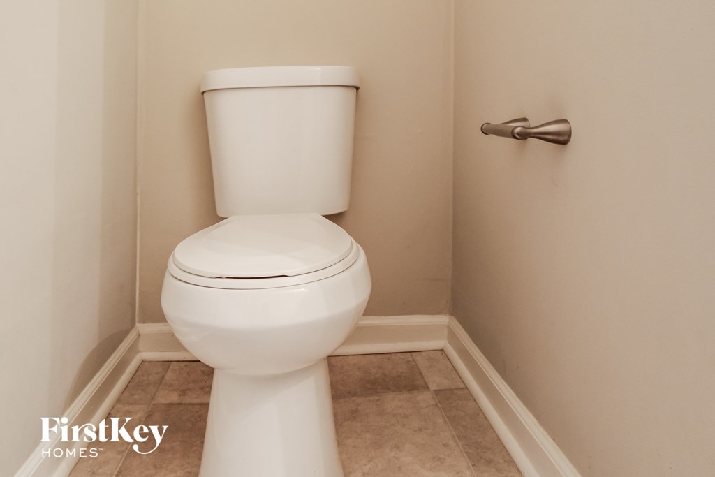 a small bathroom with a toilet and a roll of toilet paper
