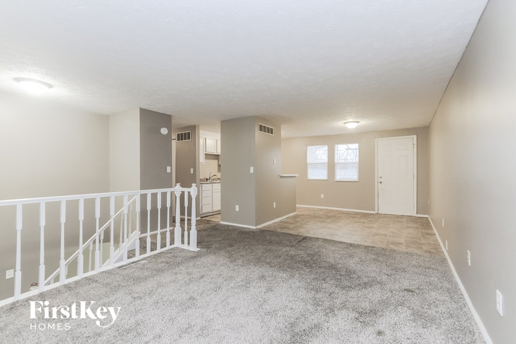 A spacious room with a carpeted floor and white railings.