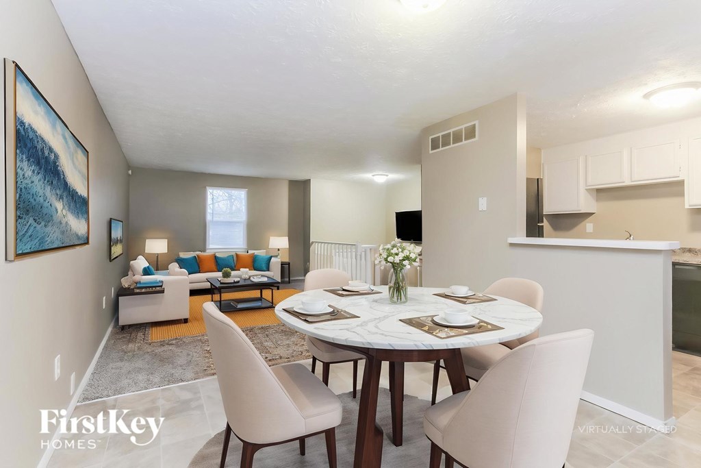 A dining room with a table set for two and a painting on the wall.