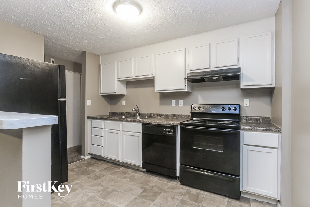 A kitchen with black appliances and white cabinets.