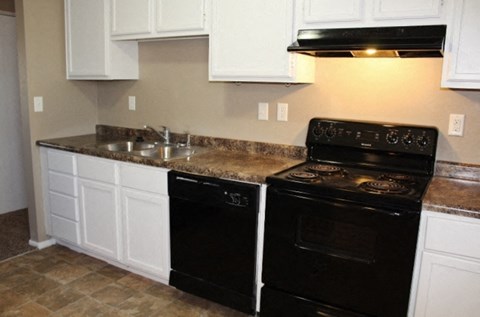 A black stove top oven sits next to a sink in a kitchen.