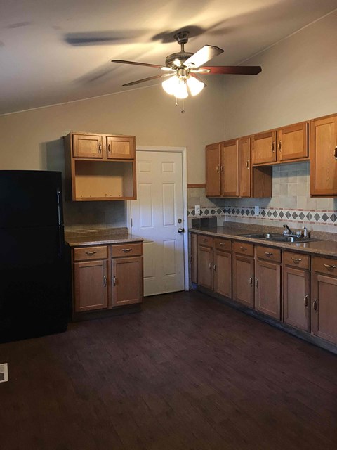 A kitchen with wooden cabinets and a black refrigerator.