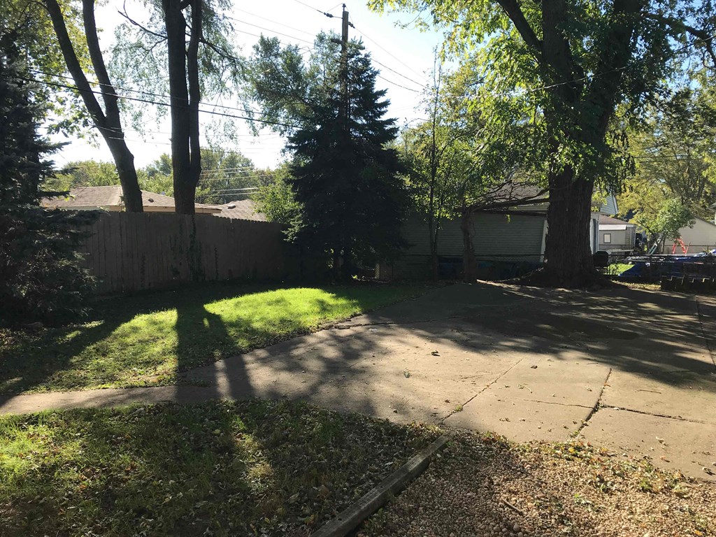 A backyard with a fence, trees, and a shed.