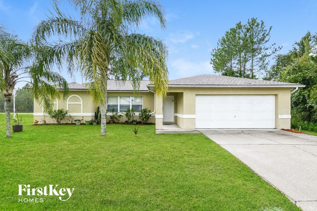 a yellow house with a lawn and palm trees