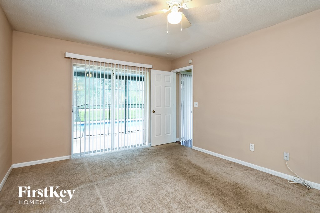 the living room of an empty home with a ceiling fan and a window