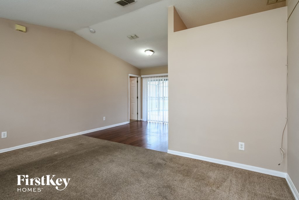 the living room and dining room of an apartment with white walls and wood flooring