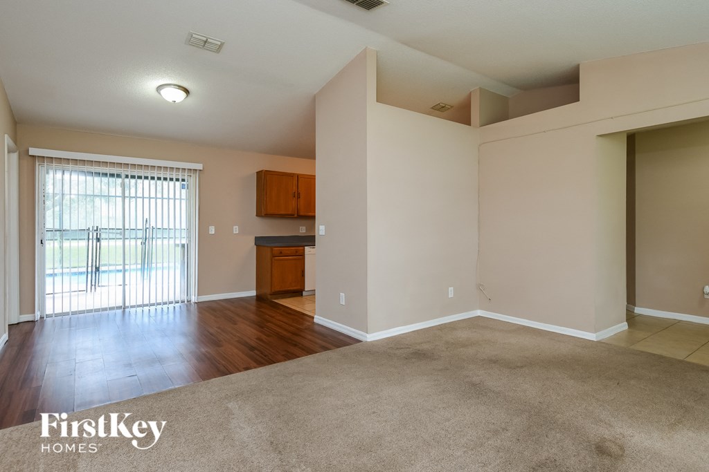 an empty living room with hard wood flooring and a window