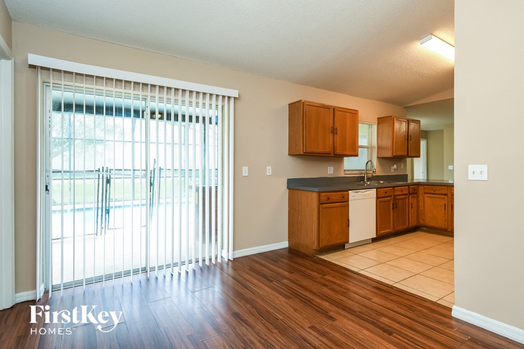 a kitchen with a large window and wooden floors and wooden cabinets