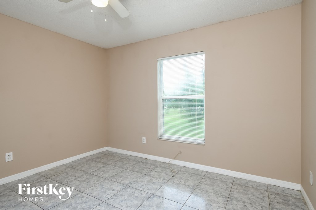 the living room of an empty house with a window and a tiled floor