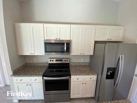 A kitchen with white cabinets and a granite countertop.