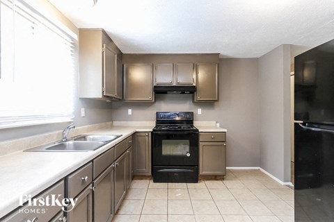 A kitchen with a black stove top oven and a black refrigerator.