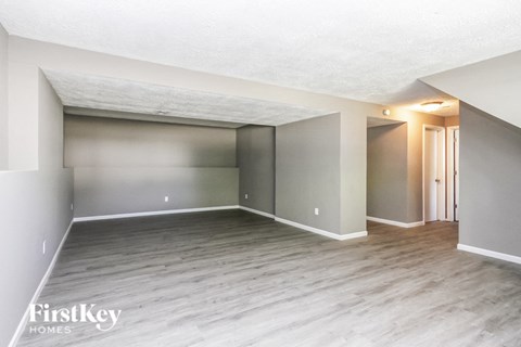 A spacious room with wooden flooring and a white ceiling.