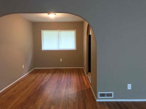 an empty living room with wood floors and a window