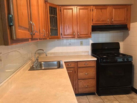 a kitchen with wooden cabinets and a sink and a stove