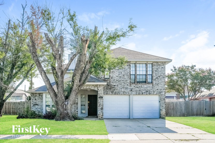 A house with a garage and a tree in front of it.