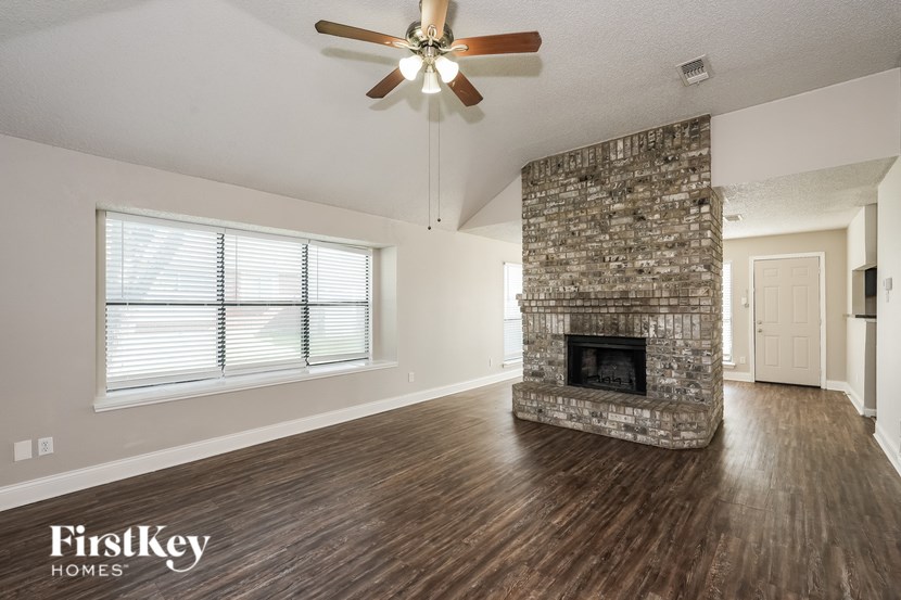 A spacious living room with a stone fireplace and wood flooring.