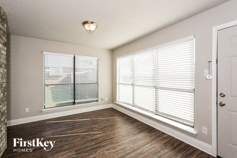 A room with wooden floors and a window with blinds.