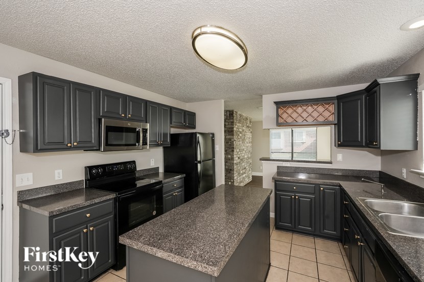 A kitchen with black cabinets and a granite countertop.