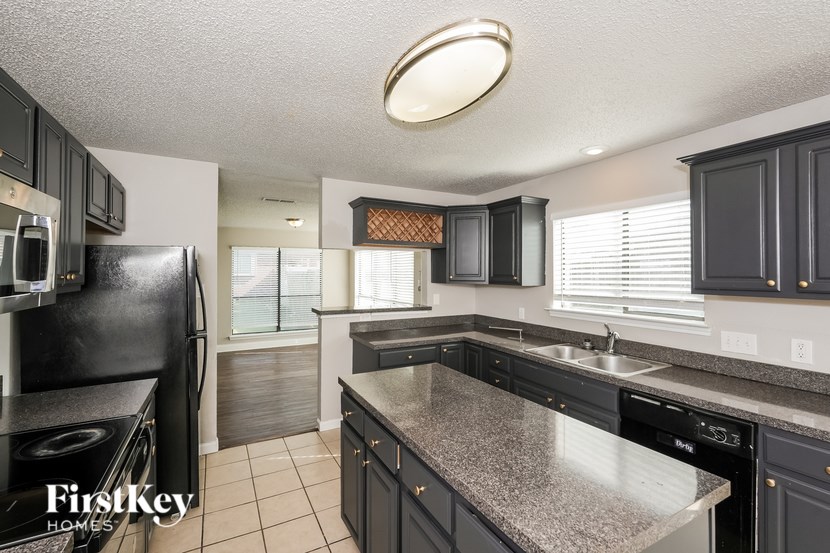 A kitchen with black cabinets and a granite countertop.