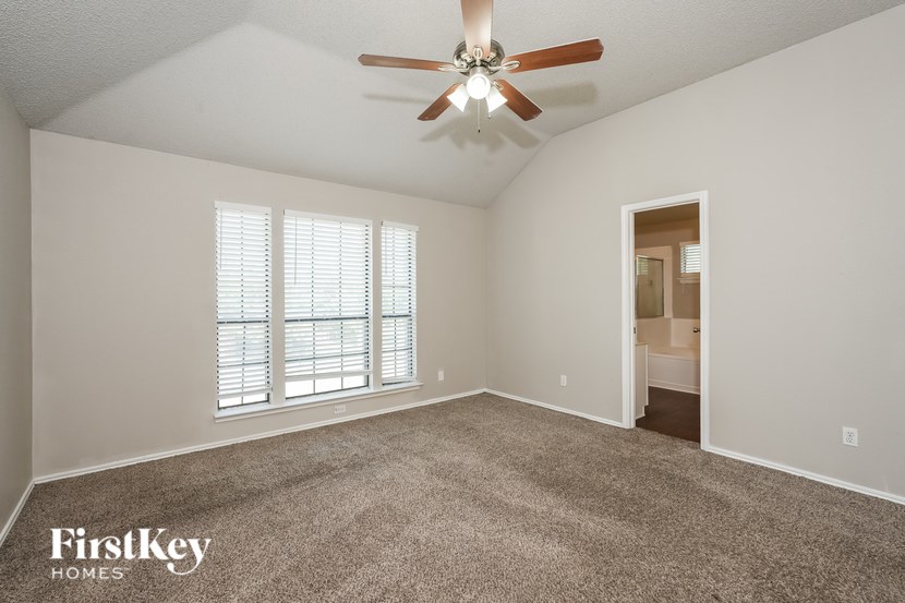 A spacious room with a ceiling fan and carpeted floor.