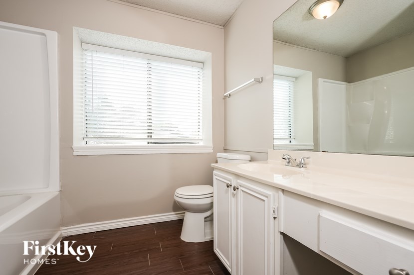 A bathroom with a toilet, sink, and window.