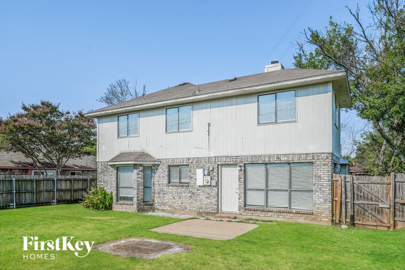 A house with a fence and a tree in front of it.