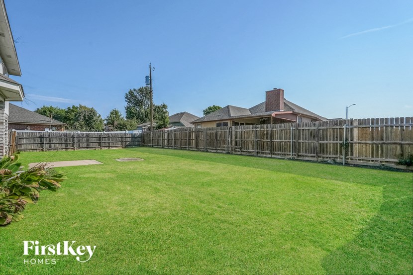 A backyard with a wooden fence and a house in the background.