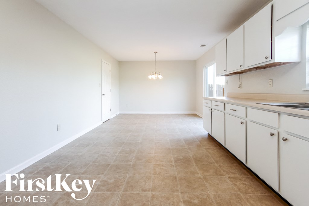 A spacious kitchen with white cabinets and a tiled floor.