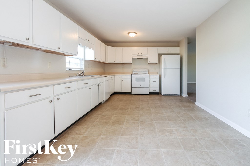 A kitchen with white cabinets and appliances in a house.