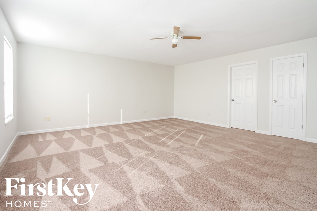 A room with a carpet and a ceiling fan.