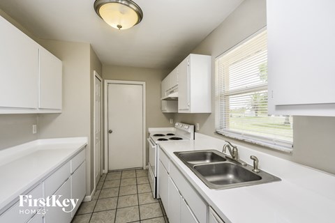 a kitchen with white cabinets and a sink and a window