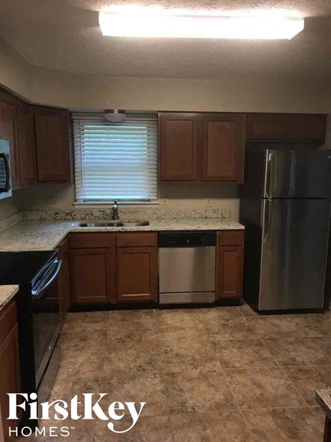 A kitchen with a refrigerator on the right and a sink in the middle.