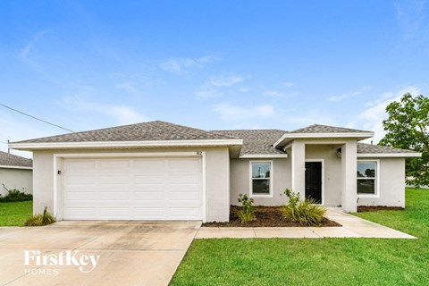 a white house with a white garage door and a lawn