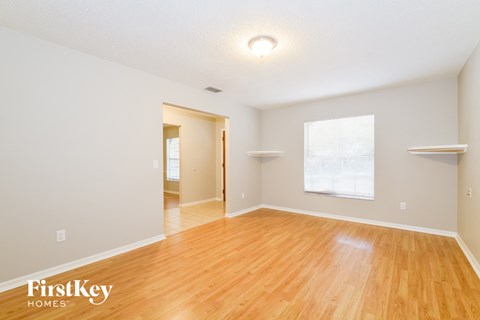 the living room and dining room with wood flooring and white walls