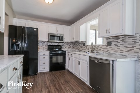 a white kitchen with black appliances and white cabinets