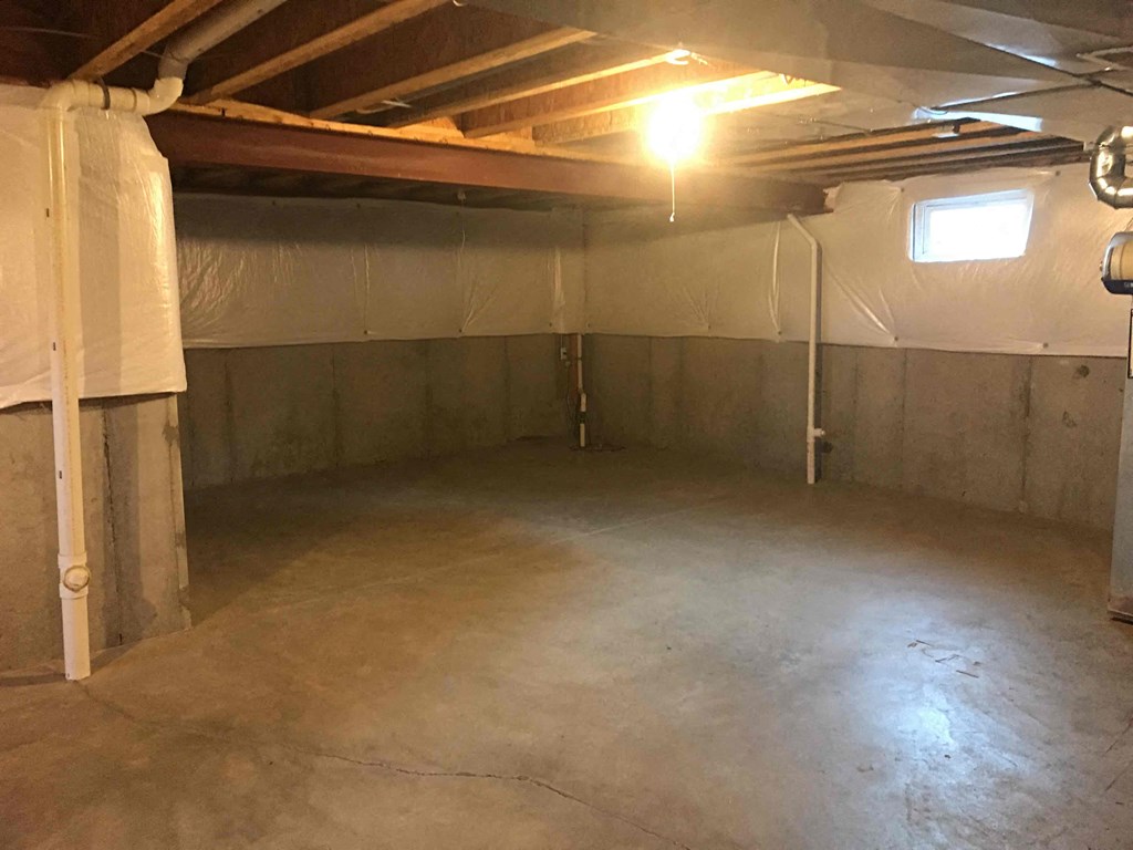 A spacious unfinished basement with a light on.