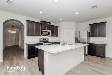 A kitchen with a white island and dark brown cabinets.