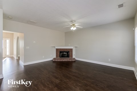 A spacious living room with a fireplace and wooden floors.