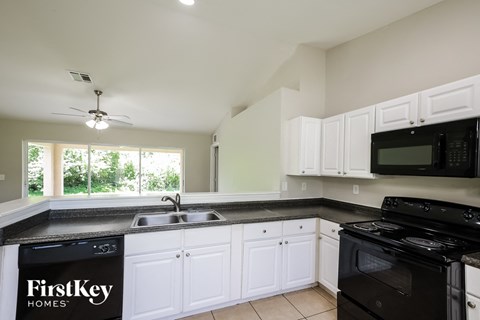 A kitchen with a black counter top and white cabinets.