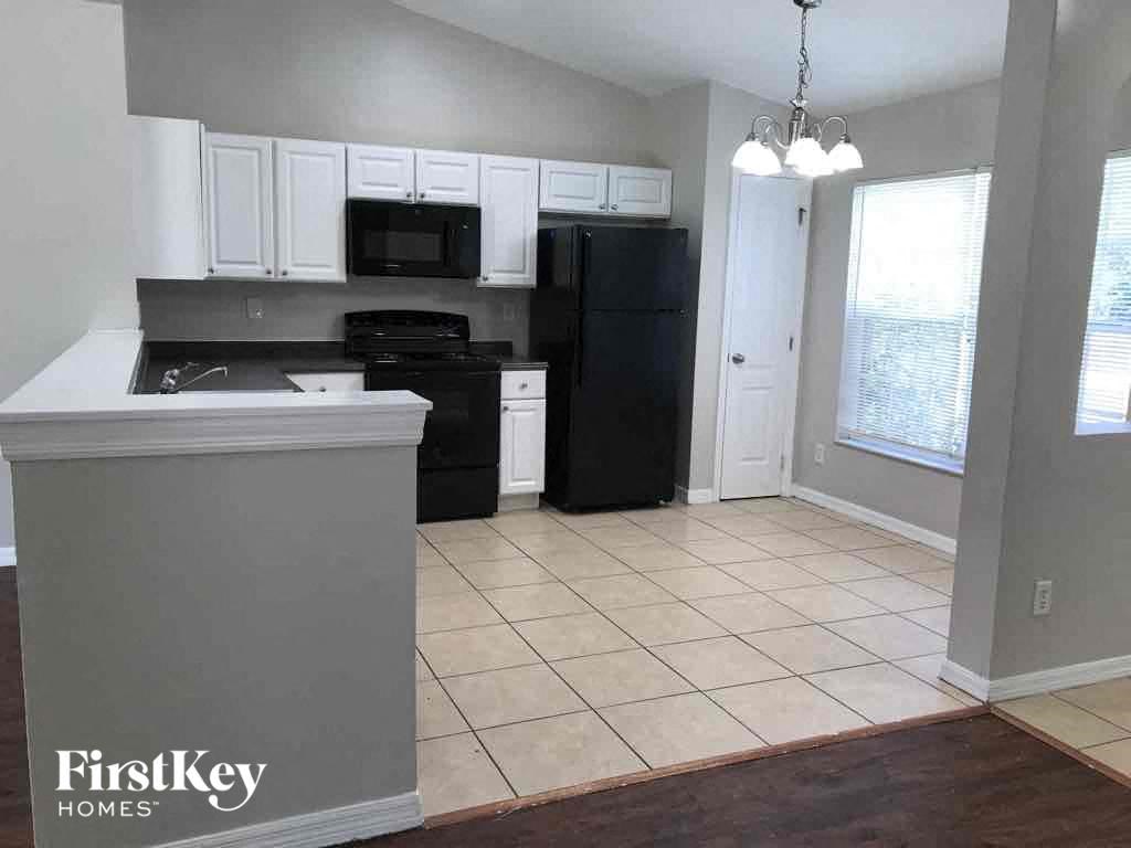 A kitchen with a black fridge and white cabinets.