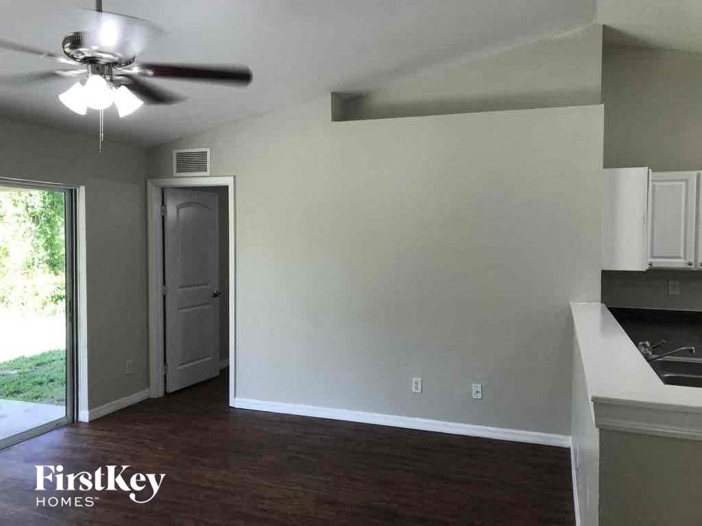 A room with a ceiling fan and a kitchen area.