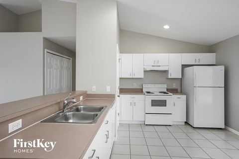 A kitchen with white appliances and a brown counter top.