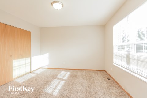a spacious living room with a large window and carpet