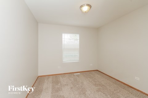a bedroom with white walls and carpet and a window