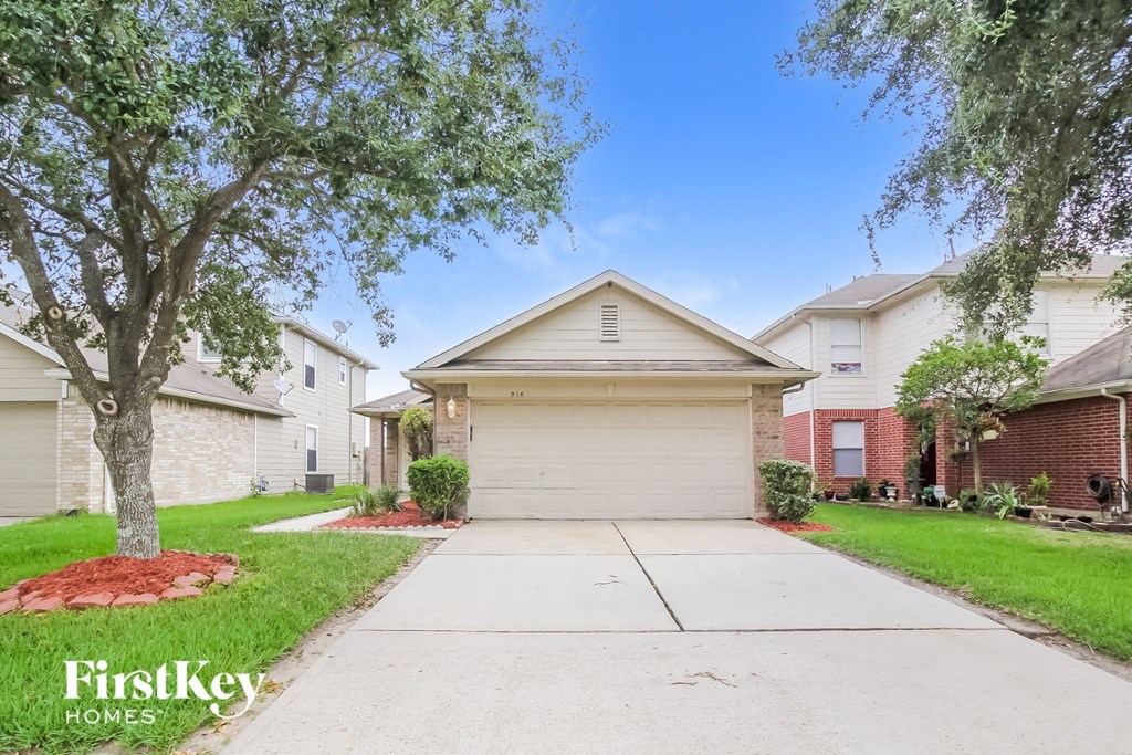 a white house with a driveway and a tree