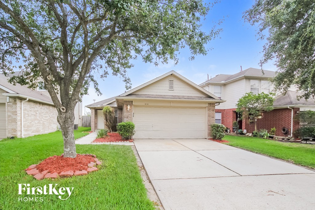 a home with a driveway and a tree in the yard